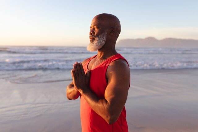 adult black man doing meditation by the beach