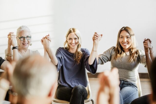 Group of diverse people holding hands up in the air