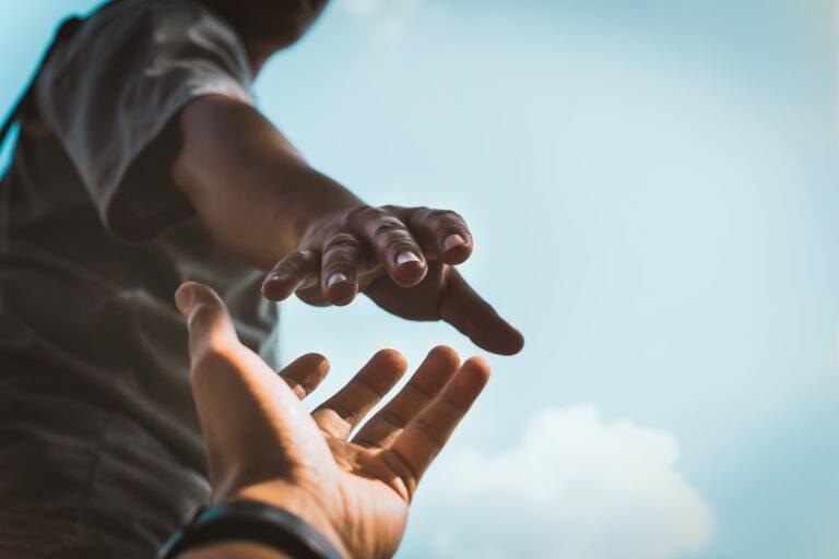 Helping hands. Image of a man holding out his hand to another person - Maui Recovery