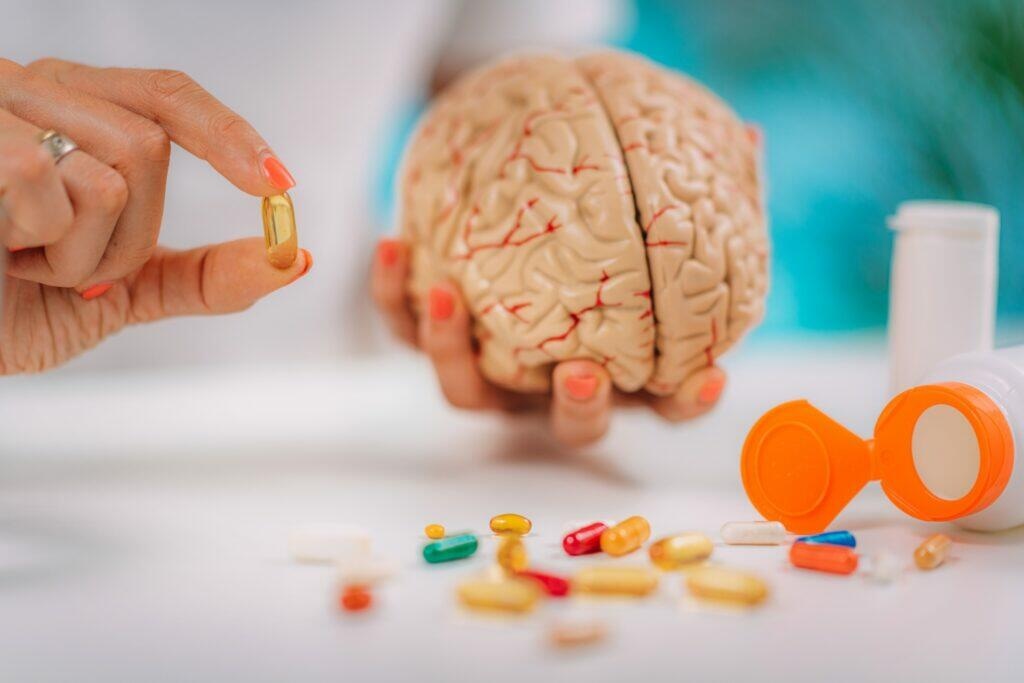 Cognitive improvement or brain supplements. Woman holding a supplement capsule and a model brain.