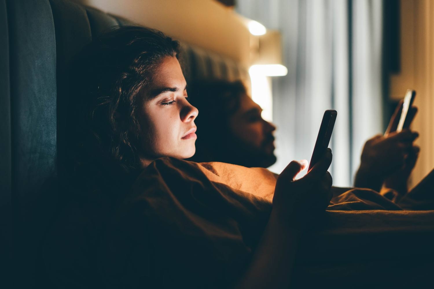 Couple with smartphones in their bed. Mobile phone addiction