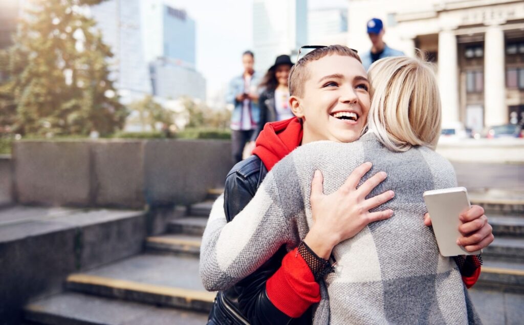 Two young female friends hugging in city