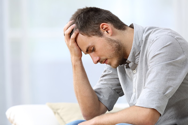 A man struggling with fentanyl addiction sits on a sofa.