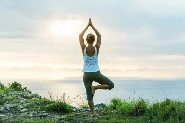 woman doing yoga by the sunset Caucasian woman practicing yoga at seashore