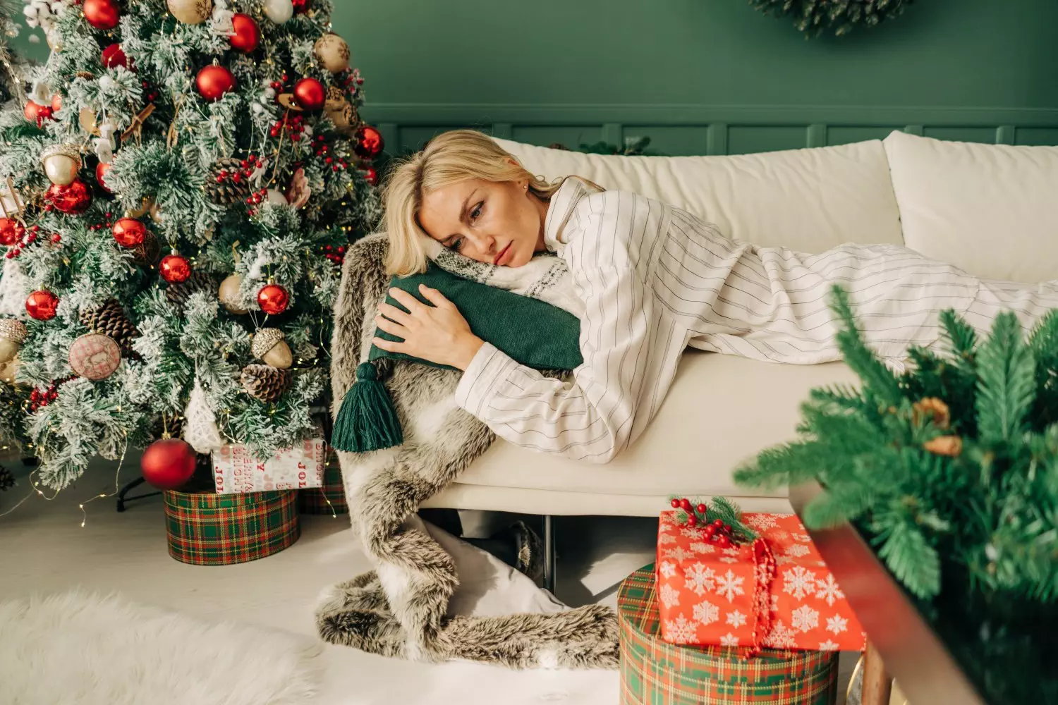 Frustrated depressive sad sick woman in pajamas lies on the sofa in christmas alone