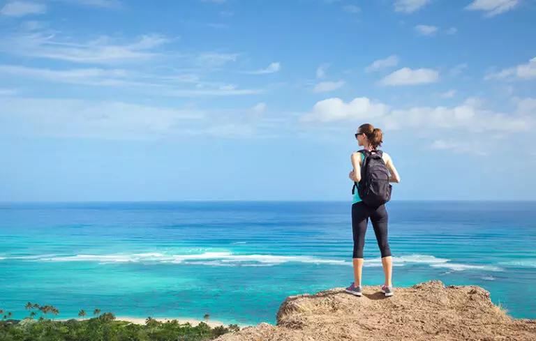 A woman takes in a view of the ocean while hiking in Hawaii, an adventure therapy practice.