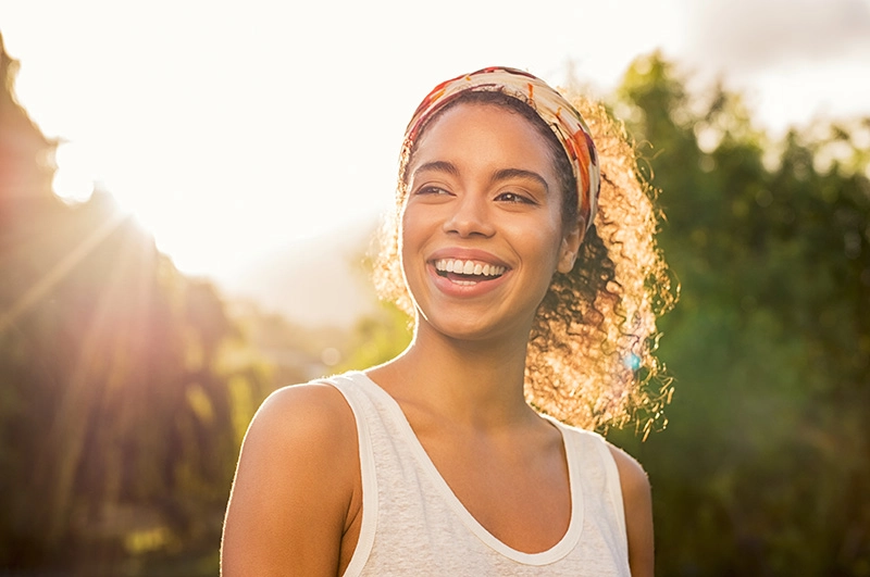 A smiling woman looks away, feeling happy that she has found hope in recovery.